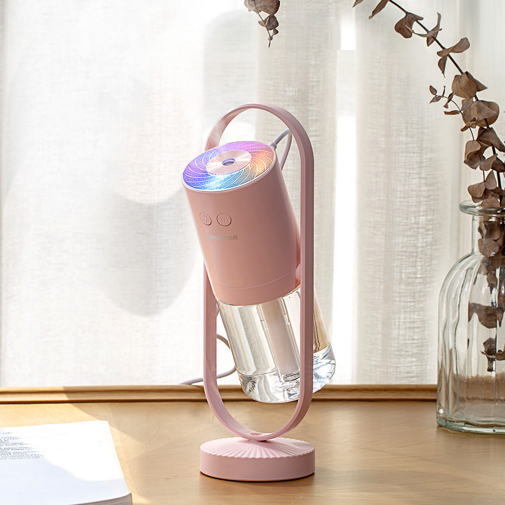 Pink portable USB humidifier with ambient glow light on desk near window